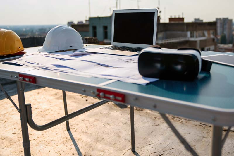 un casco con portatile e visore su un tavolo di lavoro